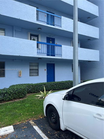 Front view of a multi-story building with blue balconies and doors.