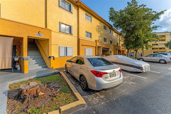 Outdoor parking area beside a three-story building with cars.