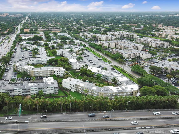 Aerial view of a suburban area with multiple residential buildings, roads, and green spaces.