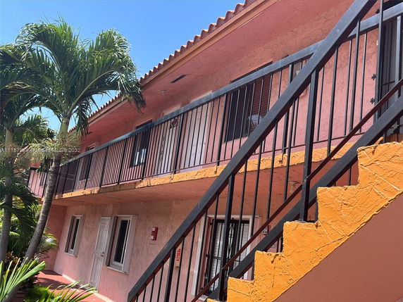 Front view of a two-story building with pink exterior and black railing on the upper level.