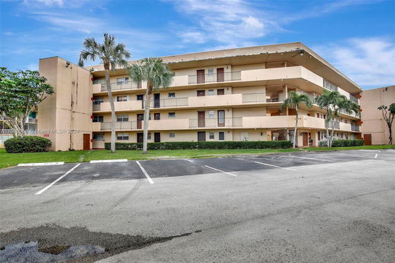 Front view of a multi-story apartment building with parking area in front.