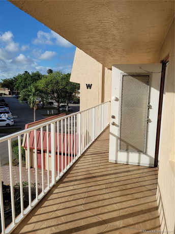View from a balcony overlooking parking and trees.