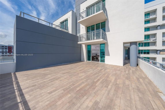 Rooftop area of a modern building with glass balcony and spacious tiled flooring.