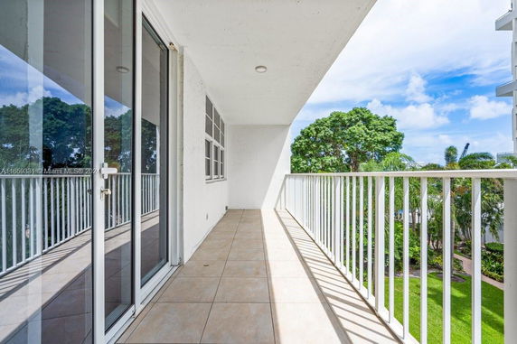 Balcony with glass doors and railing overlooking greenery