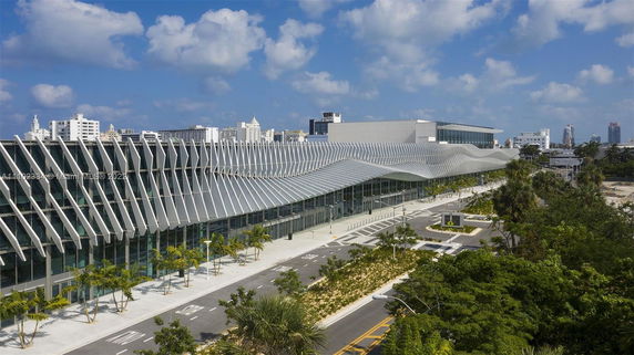 Front view of a modern building with a wavy roof and glass facade.