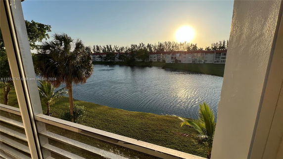 Wide view of a lake with buildings in the background and a vibrant sunset.