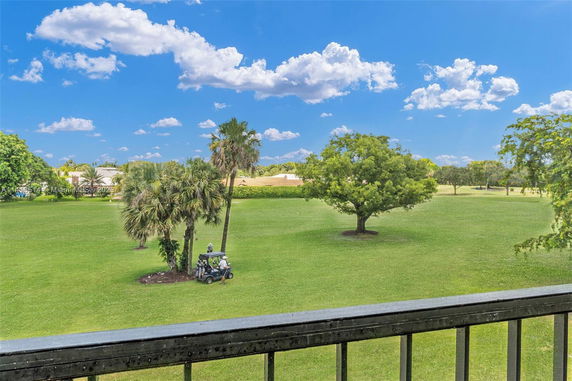 View of a grassy field with palm trees and a golf cart.