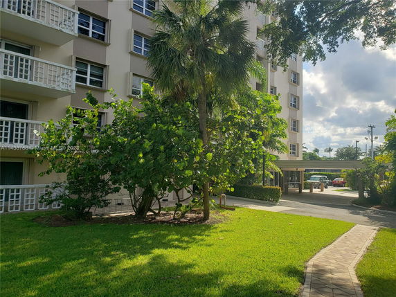 Front view of a multi-story residential building with balconies and greenery.