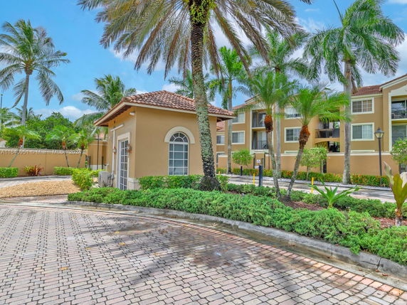 Front view of a multi-story residential building with palm trees and landscaped surroundings.