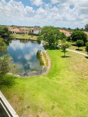 View of a lake with nearby houses and trees, under a clear sky.