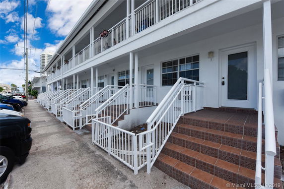 Front view of a two-story building with a series of staircases leading to entrance doors.