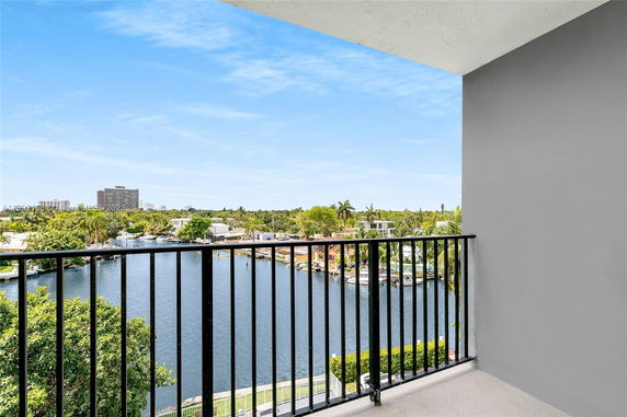 View from a balcony overlooking a waterfront area with trees and buildings in the distance.