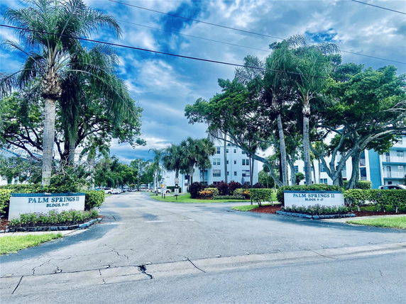 Front view of a residential complex with multiple mid-rise buildings and palm trees.