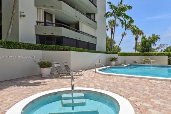 Front view of a multi-story building with balconies overlooking a pool area.