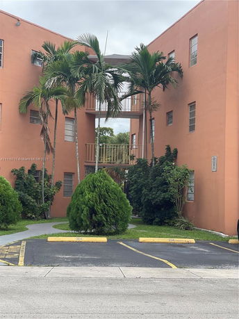 Front view of a multi-story building with an open walkway and palm trees.