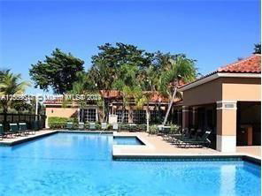 Outdoor area featuring a large swimming pool beside a building with a red tiled roof.