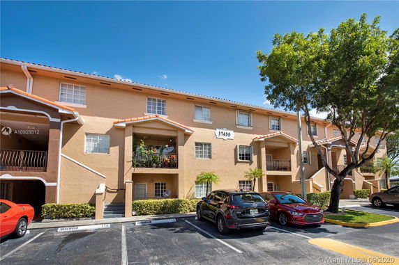Front view of a multi-story residential building with balconies and parking area.