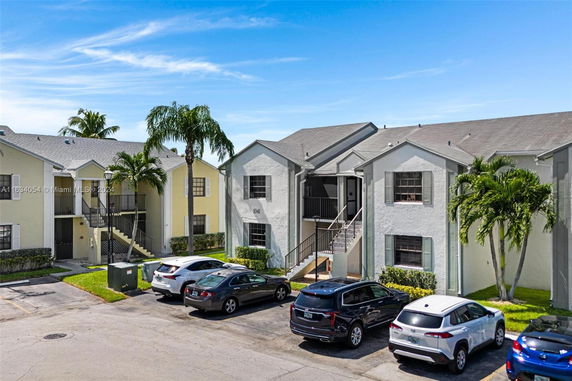 Front view of a multi-story residential building with parking area.