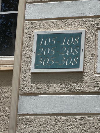 Building with textured exterior wall and a sign indicating room numbers 105-108, 205-208, 305-308.