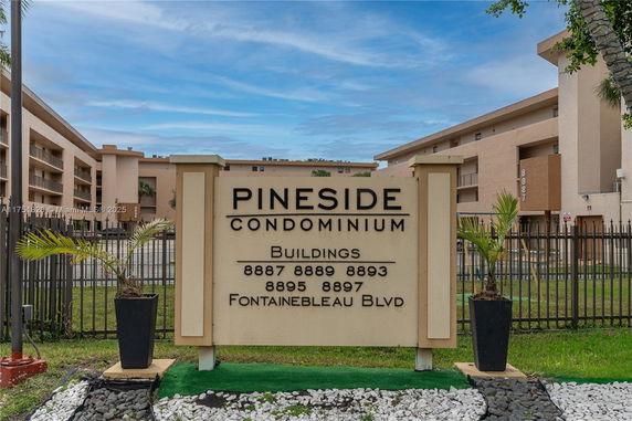 View of condominium buildings with a sign reading 'Pineside Condominium' and building numbers.