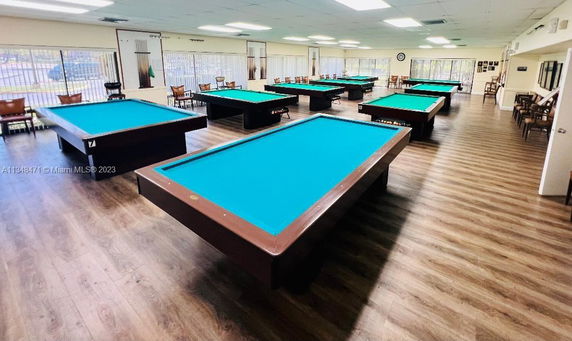 Room with multiple billiard tables and chairs arranged around them.