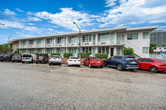 Front view of a two-story building with multiple cars parked in front.