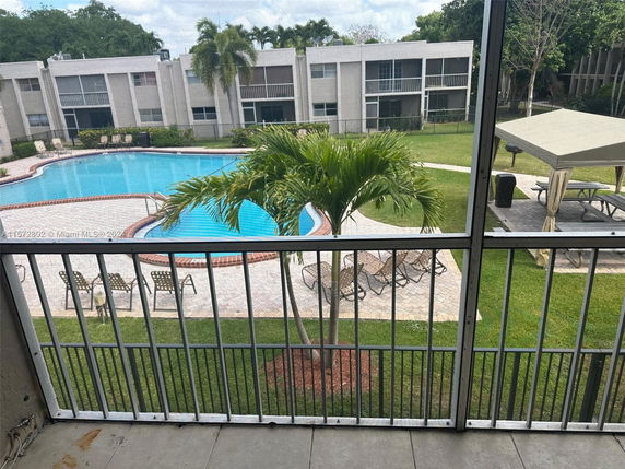 View of a swimming pool surrounded by a patio area with lounge chairs and an adjacent pavilion.