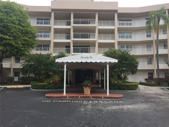 Front view of a multi-story residential building with balconies and a covered entrance.
