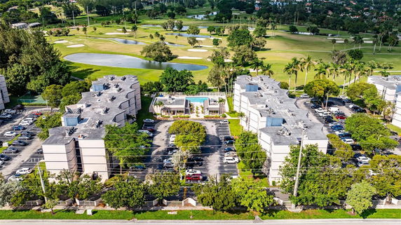 Aerial view of several residential buildings with parking lots and surrounding green areas.