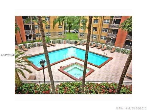 View of a swimming pool area in an apartment complex with multiple stories and balconies.