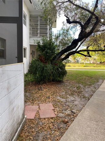 Side view of a building with a tree and plants nearby.