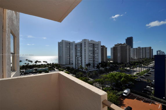 View from a balcony overlooking tall apartment buildings and a coastal area.