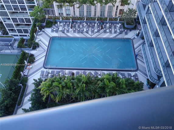 Aerial view of a swimming pool area surrounded by lounge chairs and greenery.