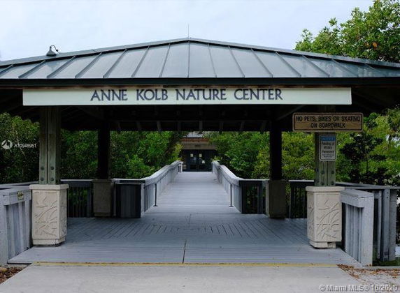 Entrance of a nature center with a covered, elevated walkway leading into a wooded area.