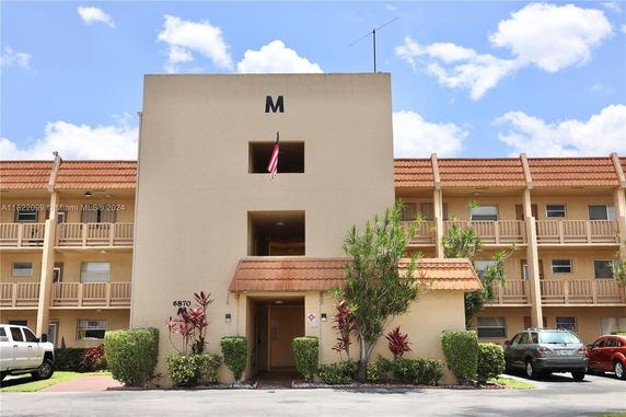 Front view of a three-story apartment building with balconies and parking area.