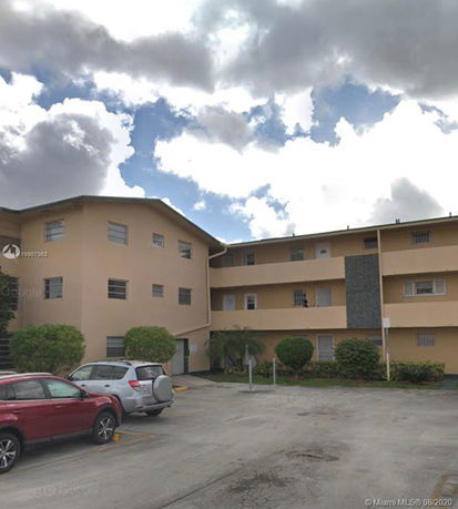 Front view of a three-story residential building with parking area.