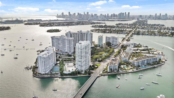 Aerial view of a waterfront cityscape with tall buildings and a bridge connecting the landmasses.