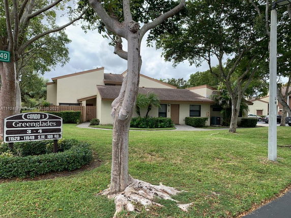 Front view of a single-story condo building with a brown roof and beige walls.