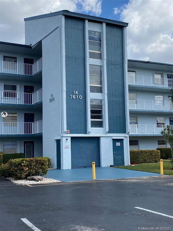 Front view of a multi-story building with balconies and a garage door.