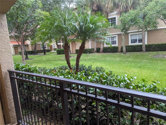View of a residential area with a lawn, trees, and multi-story houses.