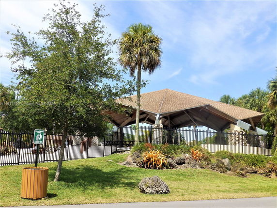 Front view of a covered outdoor structure with a pitched roof and stone pillars.