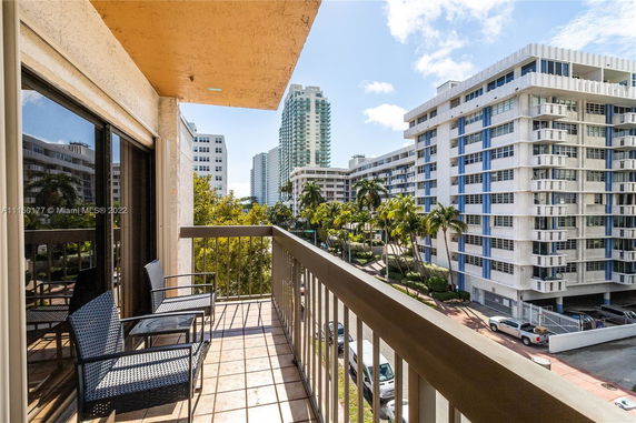View from a balcony overlooking nearby buildings and palm trees.