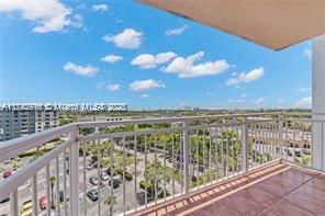 Panoramic view from a balcony overlooking a parking area and distant buildings.