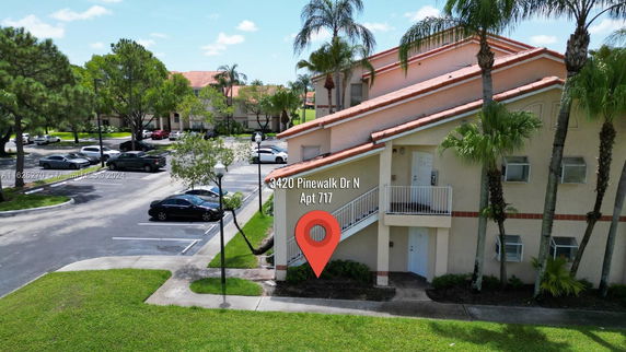 View of an apartment building with parking area and surrounding trees.