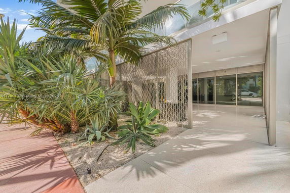 Entrance view of a modern building with glass doors and decorative metal screen.