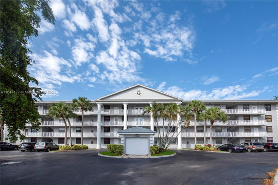 Front view of a multi-story residential building with parking area.