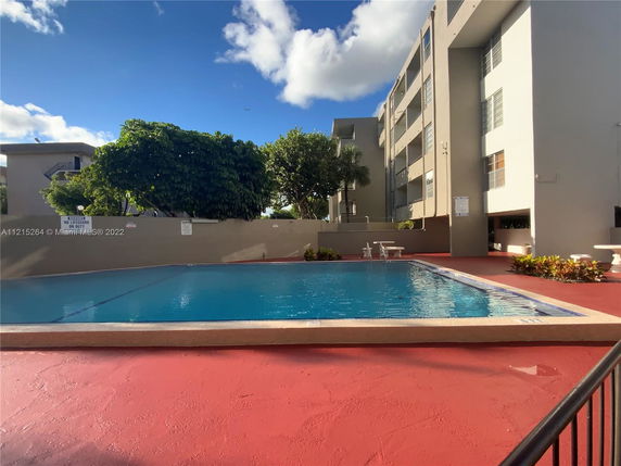 Outdoor swimming pool next to a multi-story residential building.