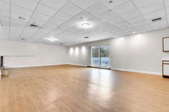 Spacious multipurpose room with wooden flooring and large sliding glass doors.