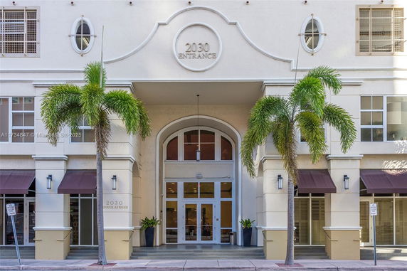 Front view of a multi-story building with palm trees at the entrance.