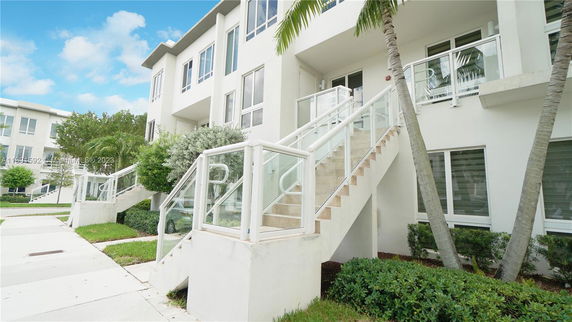 Front view of a multi-story residential building with white exterior and glass railings.